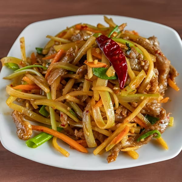 Stir-fried beef with julienned vegetables and a red chili on a white plate from Wang Chinese Restaurant.