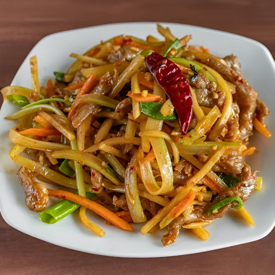 Stir-fried beef with julienned vegetables and a red chili on a white plate from Wang Chinese Restaurant.